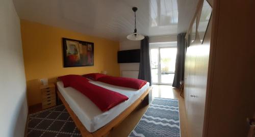 Ferienwohnung Anita Benz في Thurmansbang: غرفة نوم عليها سرير ومخدات حمراء
