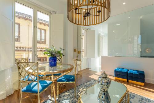 a dining room with a glass table and blue chairs at Bib Rambla Luxury Apartments in Granada