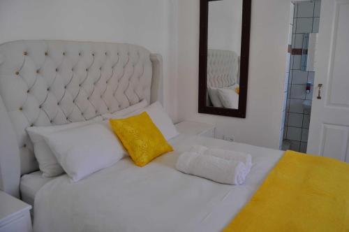 a white bed with a yellow pillow and a mirror at Timo's guesthouse accommodation in Lüderitz