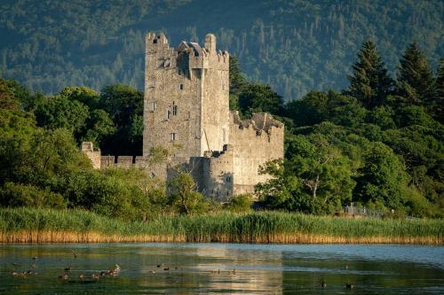 an old castle sitting on the side of a lake at Haven Suites - Killarney Self Catering in Killarney
