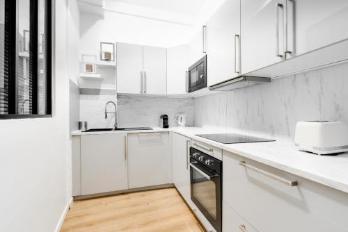 une cuisine blanche avec un évier et un lave-vaisselle dans l'établissement Chic apartment - 2BR-5P - Boulevard Saint-Germain, à Paris