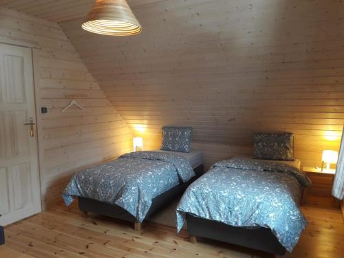 Dos camas en una habitación con paredes de madera. en Chata Lisa, en Stronie Śląskie