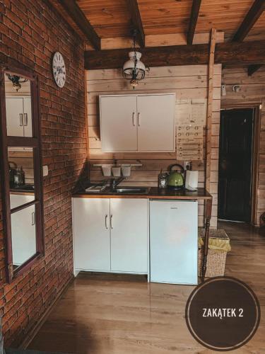 a kitchen with white cabinets and a brick wall at Chata Starych Znajomych in Sanok