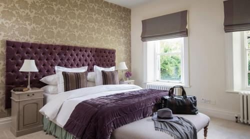 a bedroom with a large bed with a purple headboard at Ardtara Country House in Upperlands