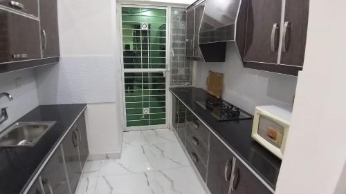 a kitchen with black and white marble floors and cabinets at Al-Nafay Guest House R1 in Lahore