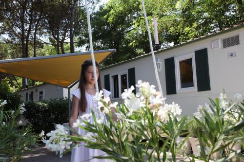 a girl in a white dress on a swing in front of a house at Dei Fiori Camping Village in Cavallino-Treporti