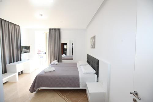 a white bedroom with a bed and a window at Nika Hotel in Sarandë