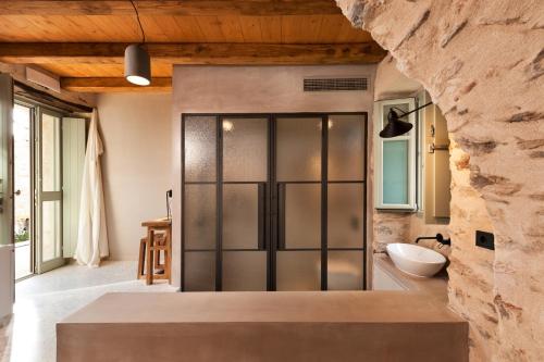 a bathroom with a glass door in a stone wall at Ruga of Vamvakou Homes in Vamvakoú