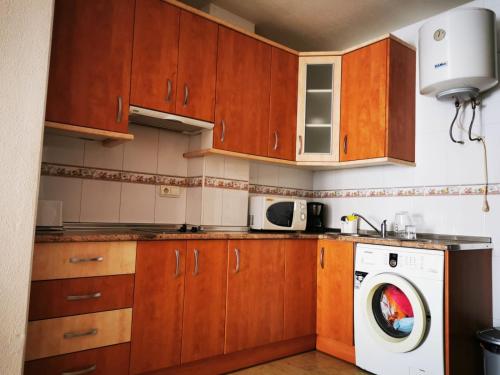 a kitchen with wooden cabinets and a washing machine at Rihuete in Puerto de Mazarrón