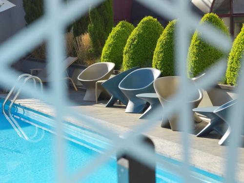 a row of chairs sitting next to a swimming pool at Novotel Metz Centre in Metz