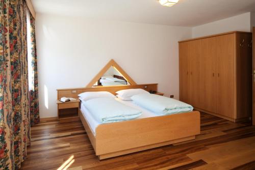 a bedroom with a bed with a wooden headboard at Ciasa Roby in San Cassiano