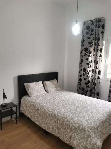 a bedroom with a bed with a black headboard and a window at Aluche Aparment C in Madrid
