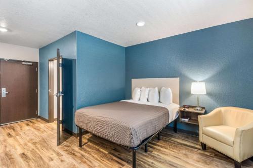 1 dormitorio con 1 cama, 1 silla y paredes azules en WoodSpring Suites Bradenton, en Bradenton