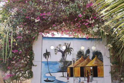 a wall with a painting of a house with pink flowers at keur manga in Somone