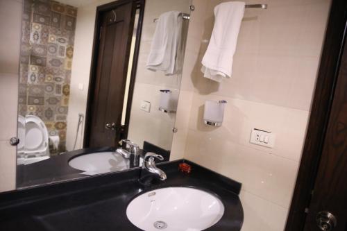 a bathroom with a sink and a mirror and towels at Hotel de Papae in Islamabad