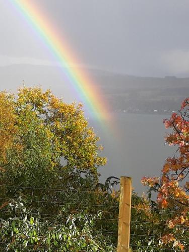 a rainbow over a body of water with a fence at Off Grid 1-Bed Cabin Pets Ok 20 mins to Dunoon in Blairmore