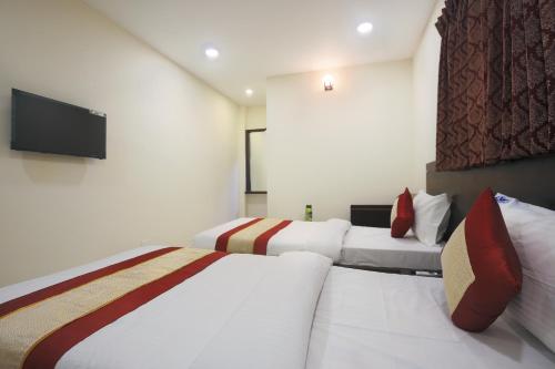 a bedroom with two beds and a flat screen tv at Balaji residency in Chennai