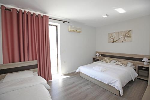a bedroom with two beds and a red curtain at Hotel Star in Sarandë