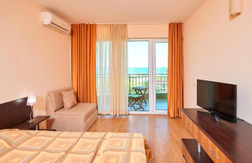 een slaapkamer met een bed, een televisie en een balkon bij Guest House California in Pomorie