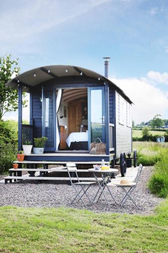 a blue tiny house with a canopy over a table at Westfield House Farm in Rothbury