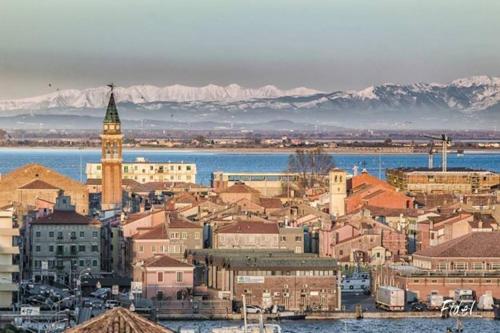 a city with a clock tower with mountains in the background at Hotel Europeo in Sottomarina