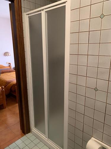 a glass shower door in a bathroom with a bedroom at Hotel Alpi - Asiago in Asiago