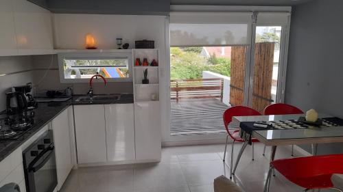 a kitchen with white cabinets and a table with red chairs at dolce casa 2 in San Clemente del Tuyú