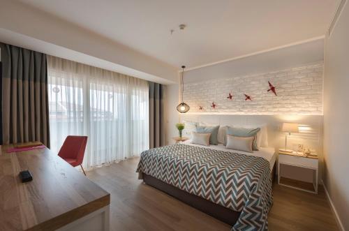 Habitación de hotel con cama, escritorio y ventana en Akra Kemer - Ultra All Inclusive en Kemer