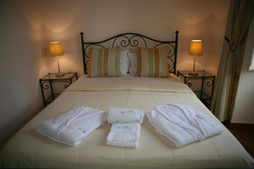 two towels sitting on a bed with two lamps at Casa Antiga in Odeceixe