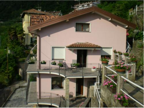a pink house with flowers on the balconies at Casa Nora in Dervio
