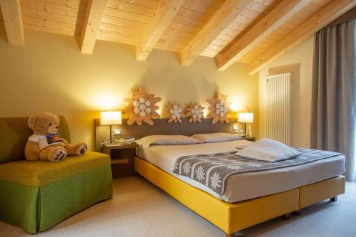 een slaapkamer met een bed en een teddybeer op een stoel bij Chalet Tovel - Mountain Lake in Tuenno