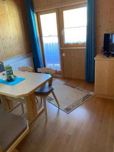 a room with a table and chairs and two windows at Ferienwohnungen Marchanger in Niederau