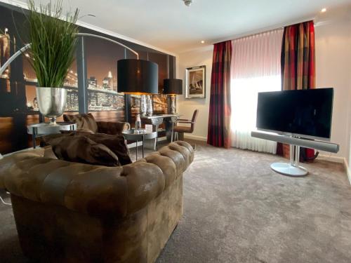 a living room with a large couch and a television at Parkhotel Bielefeld in Bielefeld