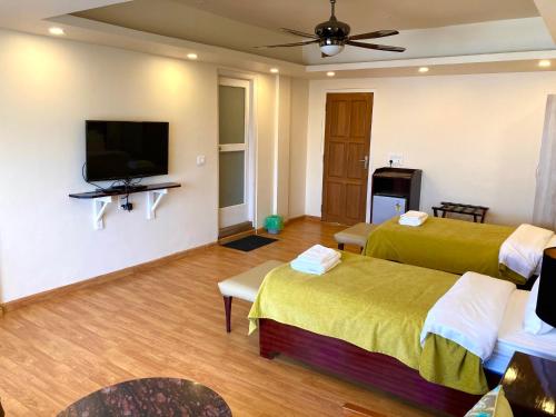 a hotel room with two beds and a flat screen tv at Shalom Farmhouse by the hillside in Imphal