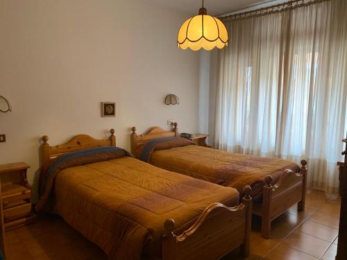 a bedroom with two beds and a chandelier at Hotel Alpi - Asiago in Asiago