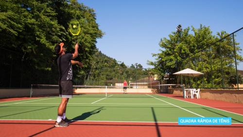 a man holding a tennis racquet on top of a tennis court at Vila Galé Eco Resort Angra - All Inclusive in Angra dos Reis