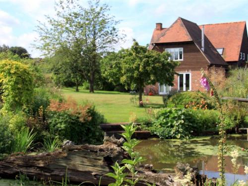 a house and a pond in front of a house at Field Farm Cottage B&B in Reading