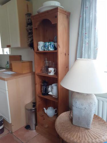 a lamp sitting on a stool next to a shelf at Field Farm Cottage B&B in Reading