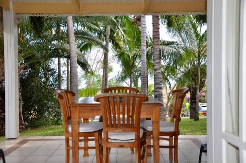 a table and chairs on a porch with palm trees at Cases Couleurs in Saint-Leu