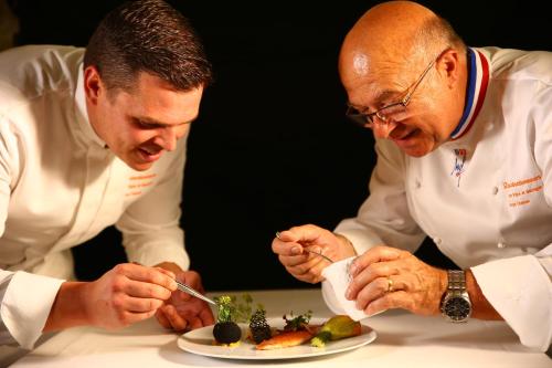two men are eating a plate of food at Maison CHENET - Les Chambres Entre Vigne et Garrigue - Teritoria in Pujaut