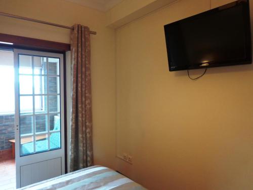 a bedroom with a flat screen tv on the wall at O Vicente in Loriga