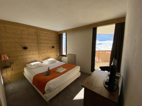 Hotel Le Portillo في فال تورن: غرفة نوم بسرير ومكتب ونافذة