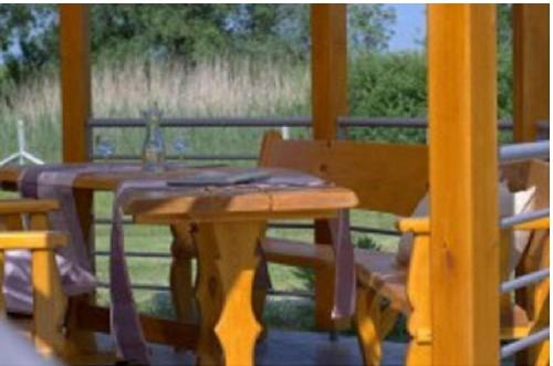 a wooden table and bench on a porch at Bungalow in Tiszagyenda