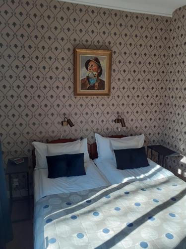 a bedroom with a bed with a picture on the wall at Hotell S:t Olof in Falköping