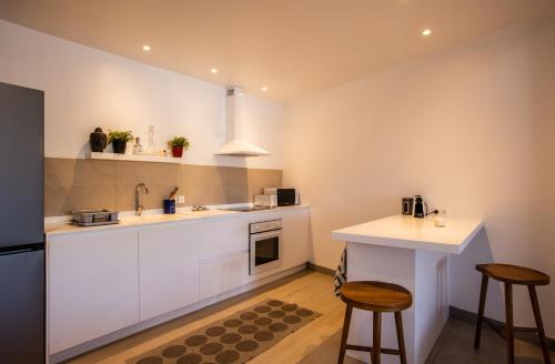 a kitchen with white cabinets and a table and stools at Stunning New apartment with view of Orient Bay in Orient Bay