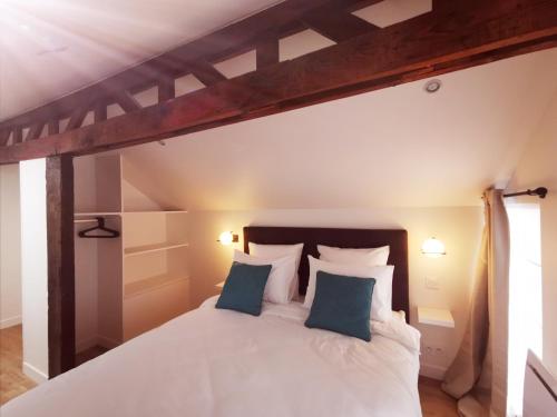 une chambre avec un grand lit blanc avec des oreillers bleus dans l'établissement Villas Chapu, à Fontainebleau