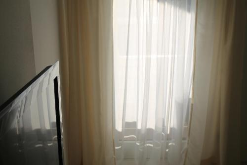 a window with a white curtain and a tv at Haus Sonnenblick in Lam