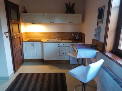 eine Küche mit weißen Schränken, einer Spüle und einem Tisch in der Unterkunft Studio Gdańsk in Danzig