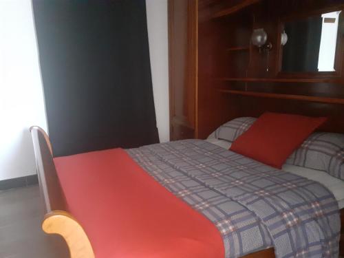 um quarto com uma cama com uma almofada vermelha em Petite Maison Chalet à 100 m de la petite mer de Gâvres em Riantec