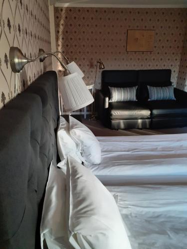 a bedroom with a bed with a lamp and a couch at Hotell S:t Olof in Falköping
